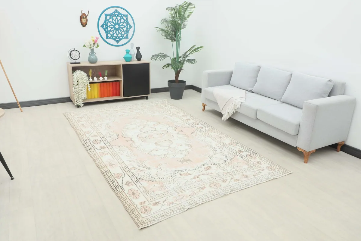 Rose and ivory vintage rug placed in a living room setting with a light gray sofa