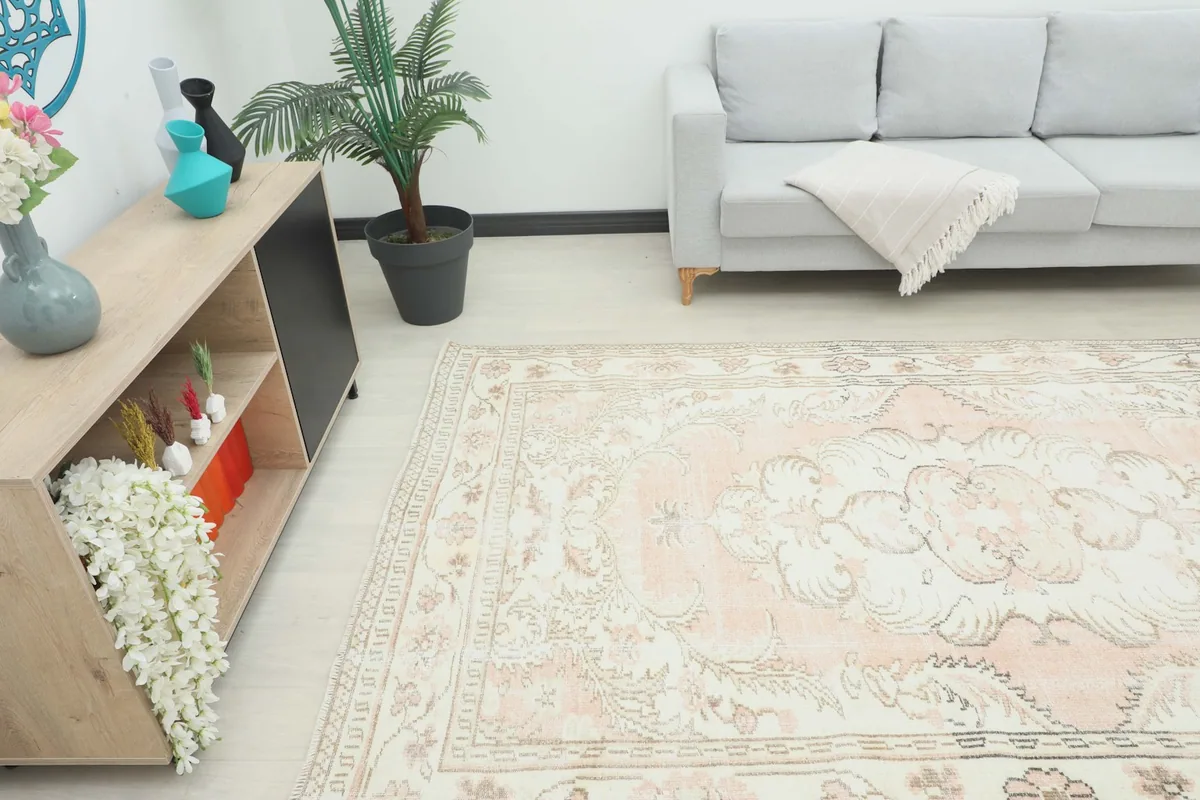 Angle view of the rose and ivory vintage rug in a room, showing its placement next to a console