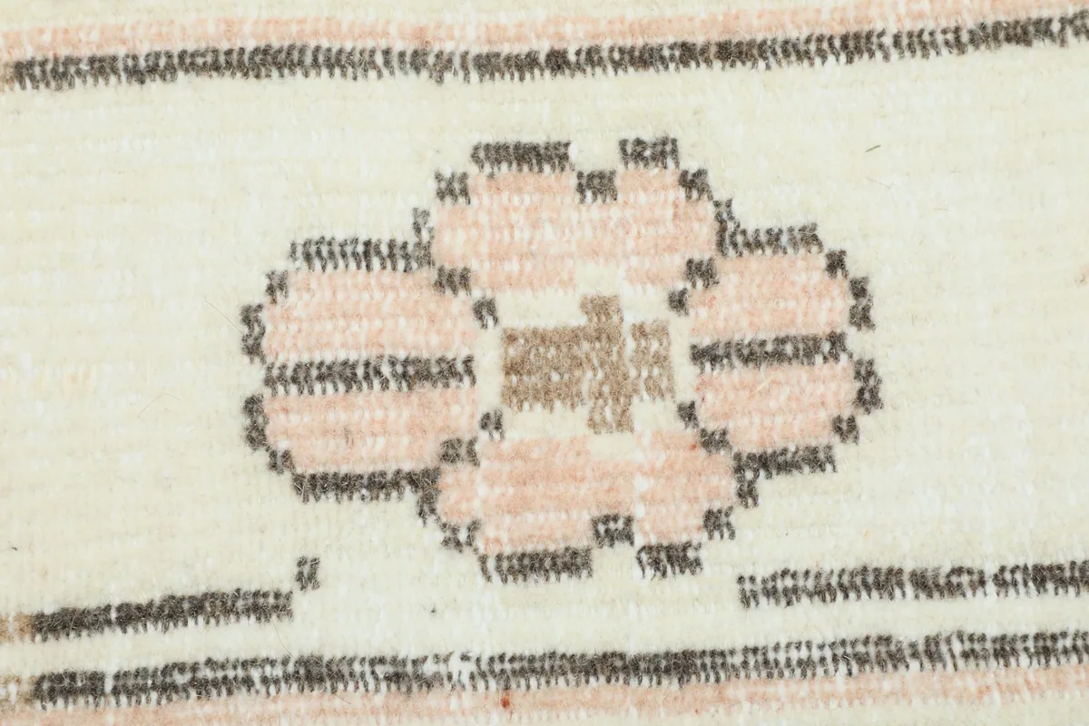 Close-up of a floral motif in rose and brown within the rug's border design