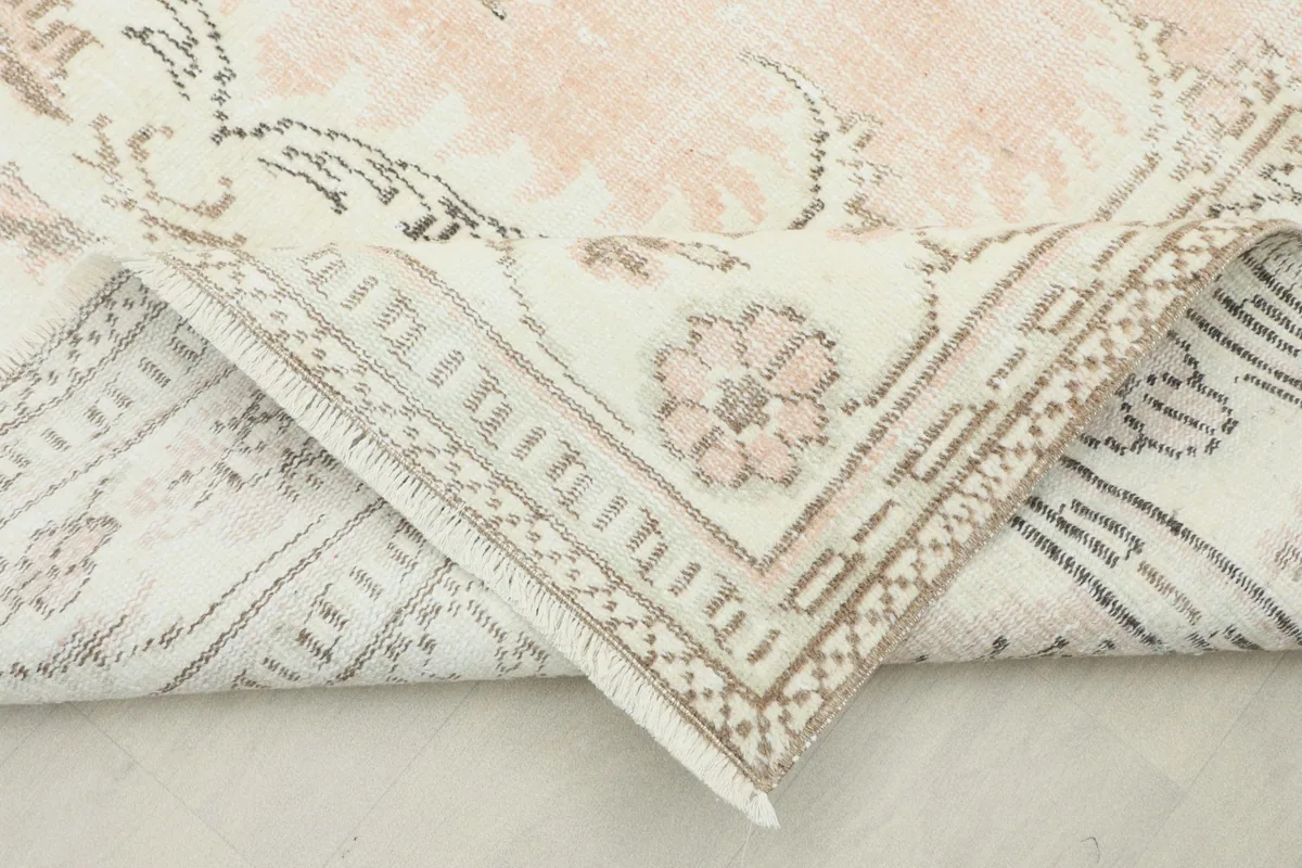 Corner of the vintage rug folded back, revealing the reverse side and knotting