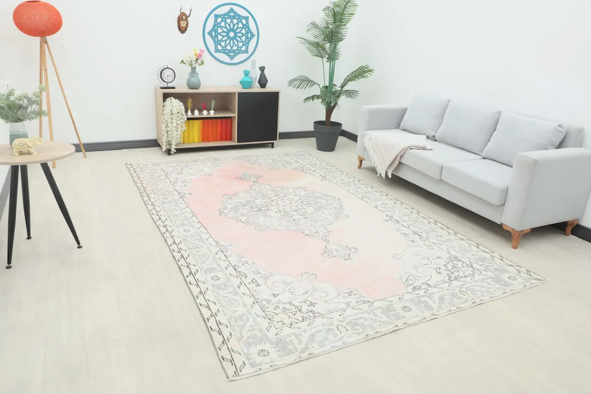 Angle view of the pink and gray vintage area rug in a modern living room setting with a light gray sofa.