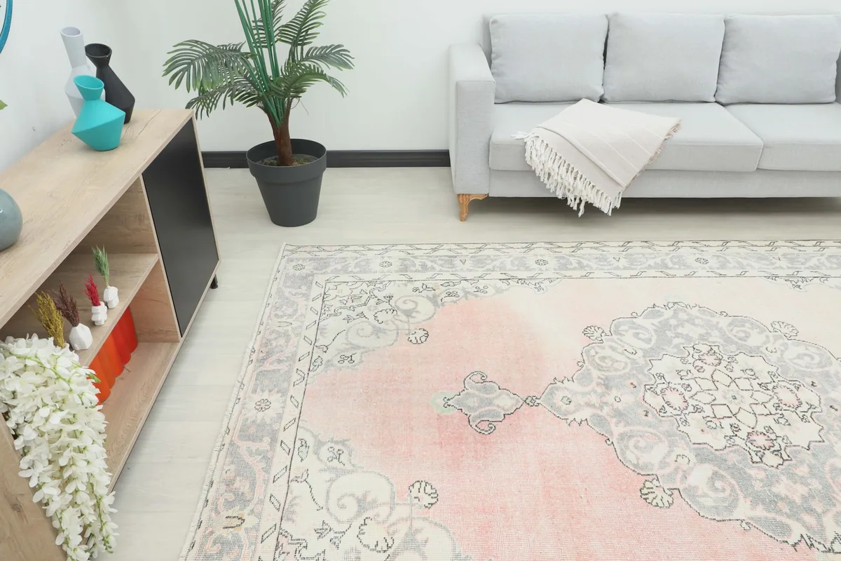Overhead angle view of the pink and gray rug placed in a room with a sofa and side table, showing its scale.