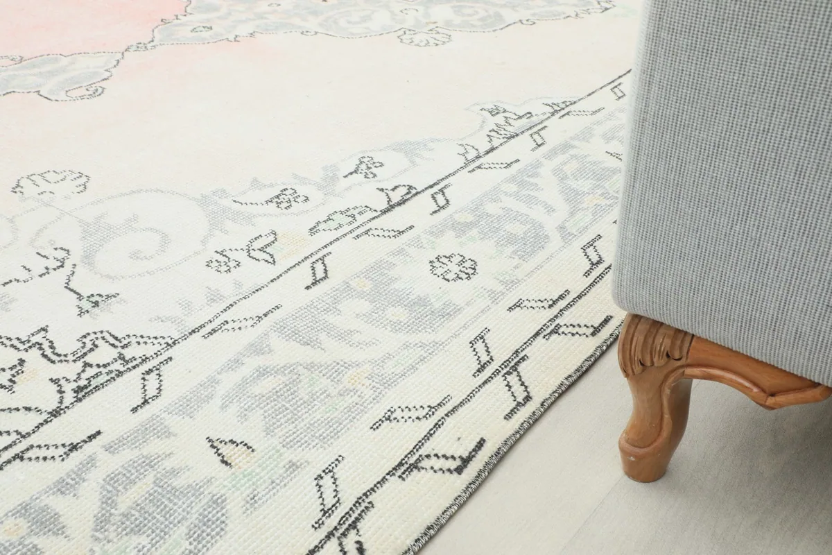 Detail of the rug's border next to a gray ottoman, illustrating how the rug fits into a living space.