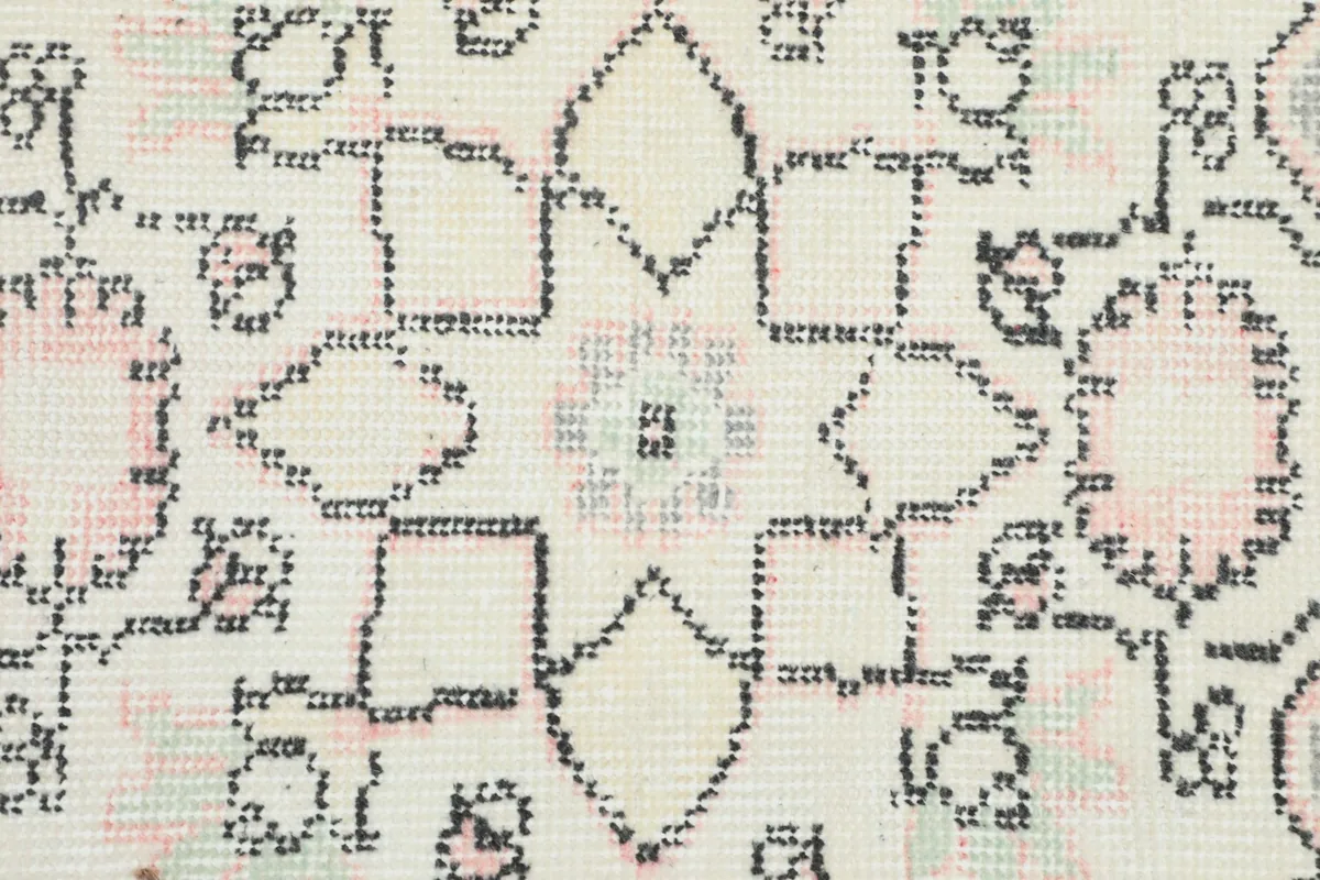 Close-up of the geometric and floral motifs within the rug's ivory and gray pattern, showing wool texture.