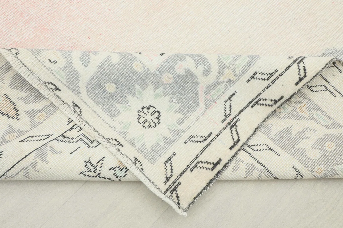 Folded corner of the rug revealing the tightly hand-knotted cotton foundation and the reverse side of the pattern.