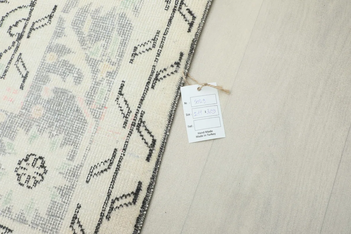 Corner of the rug with a product tag, showing the reverse side of the border and knotting.