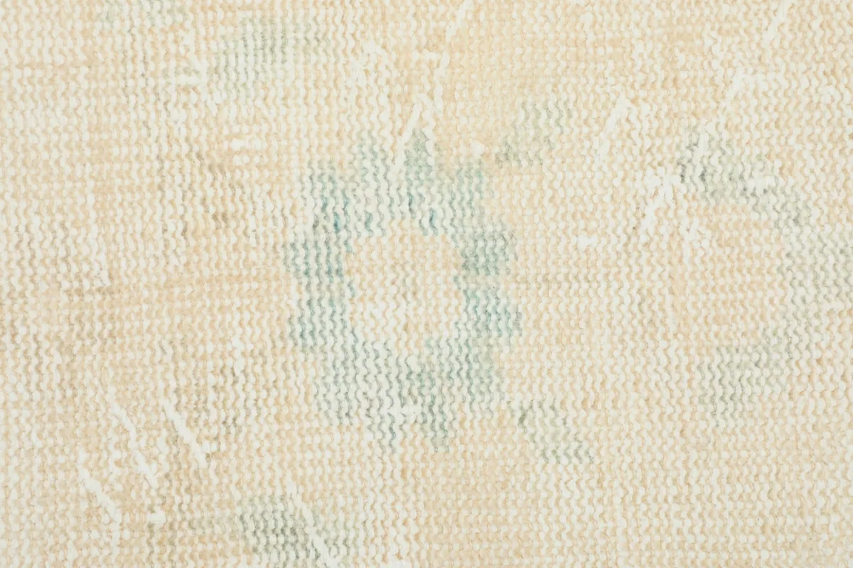 Close-up showing the subtle wear and distressed look of the wool pile and floral pattern.