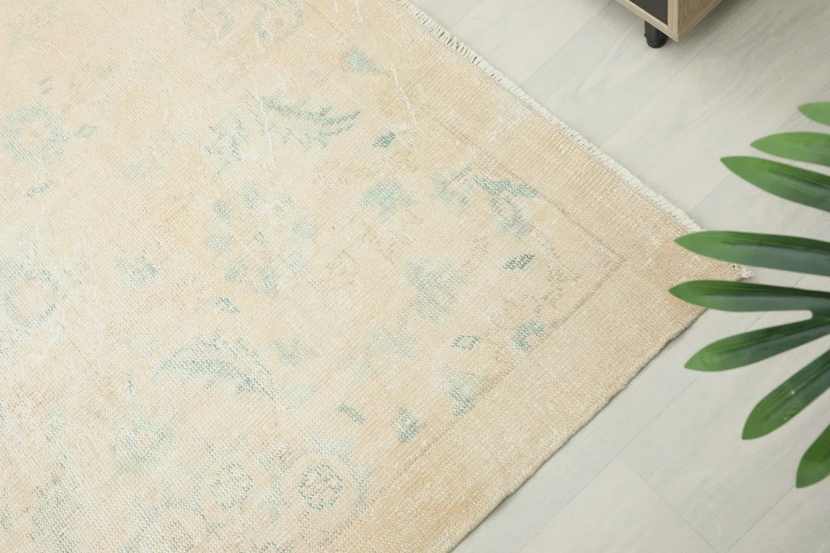 Corner view of the rug's border design, showcasing the delicate patterns and faded appearance.