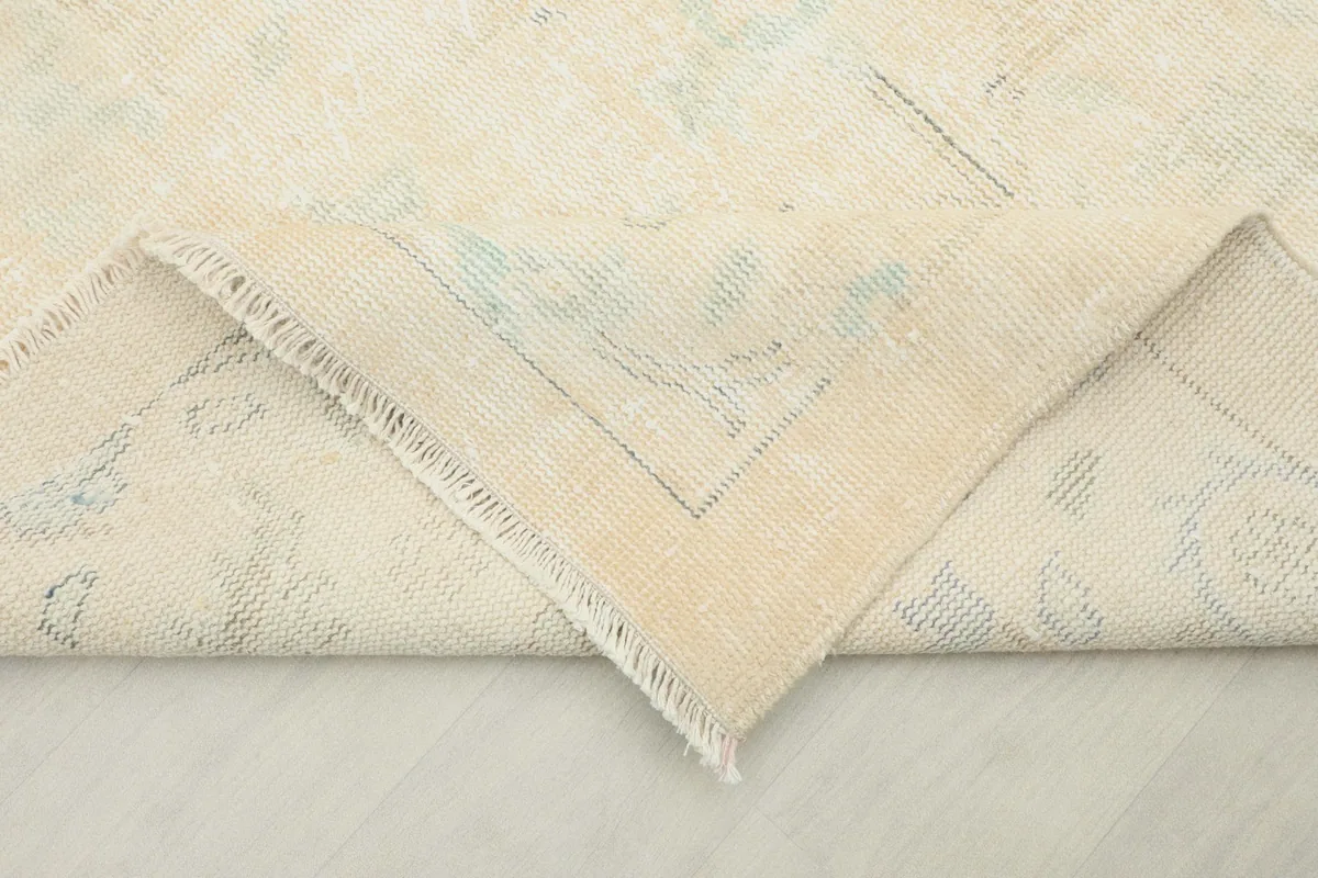 Folded corner of the rug revealing the hand-knotted cotton foundation and reverse side of the wool pile.