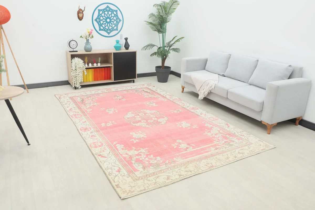 Vintage pink rug displayed in a living room setting with a light-colored sofa