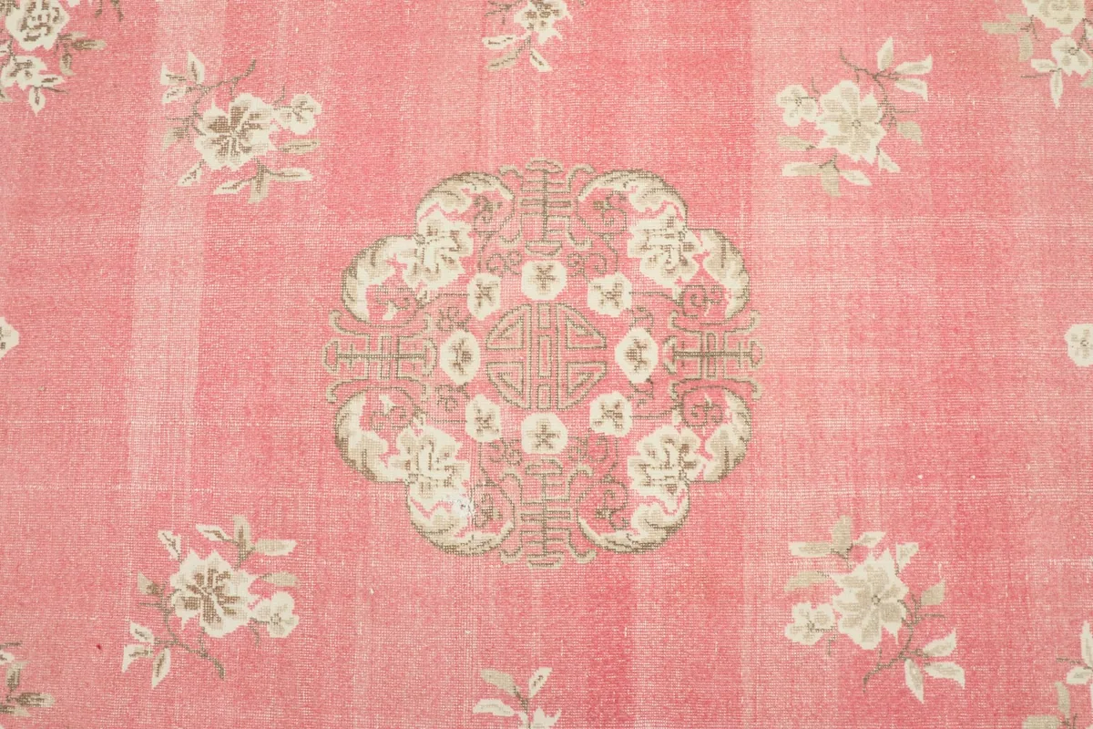 Close-up of the central medallion and surrounding floral motifs on the pink field
