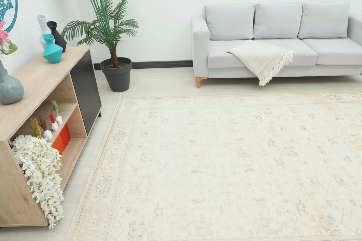 View of the large cream rug in a living room setting, complementing a light gray sofa.