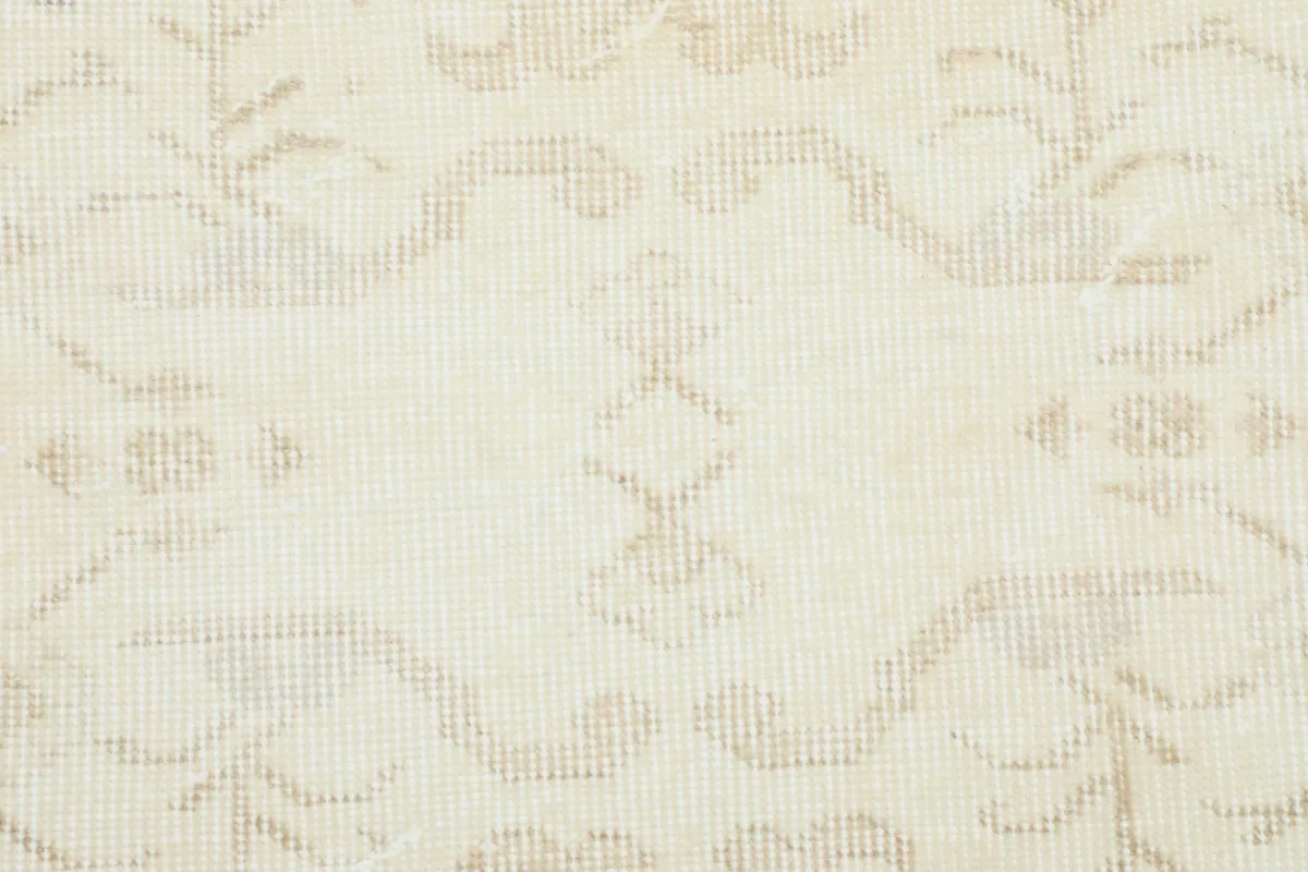 Extreme close-up showing the low pile texture and muted pattern details of the wool rug.