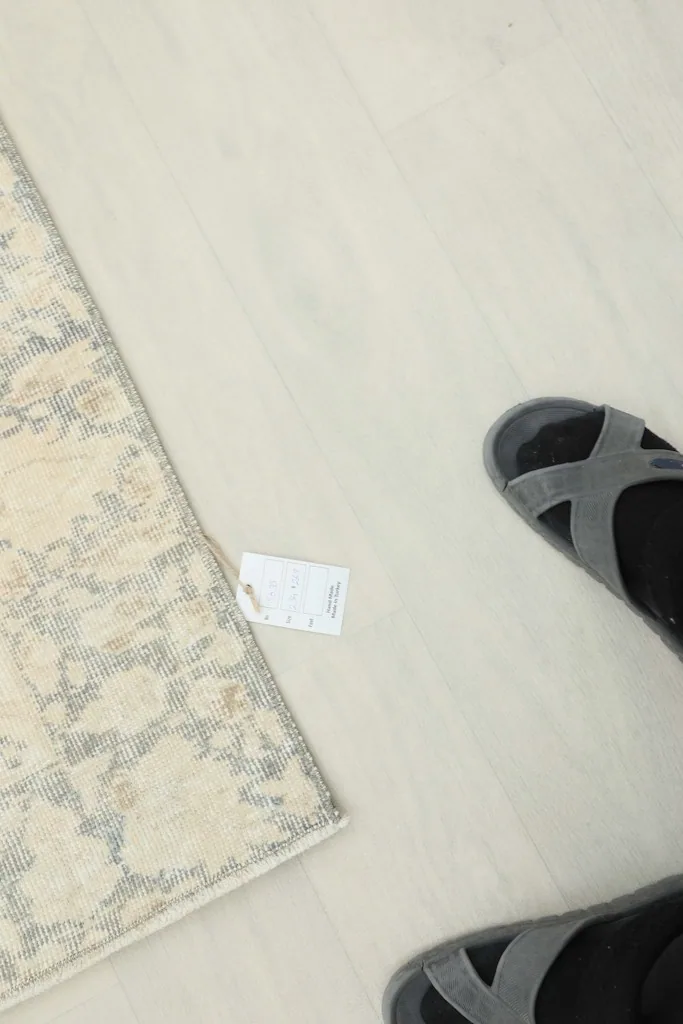 Overhead view of a small section of the rug with a size tag and feet for scale