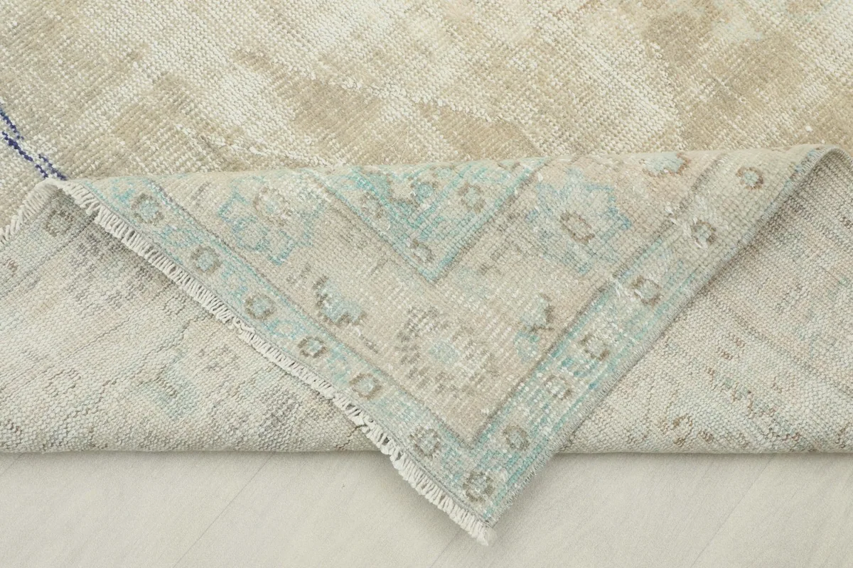 Folded corner of the rug revealing the cotton foundation and the reverse side of the hand-knotting