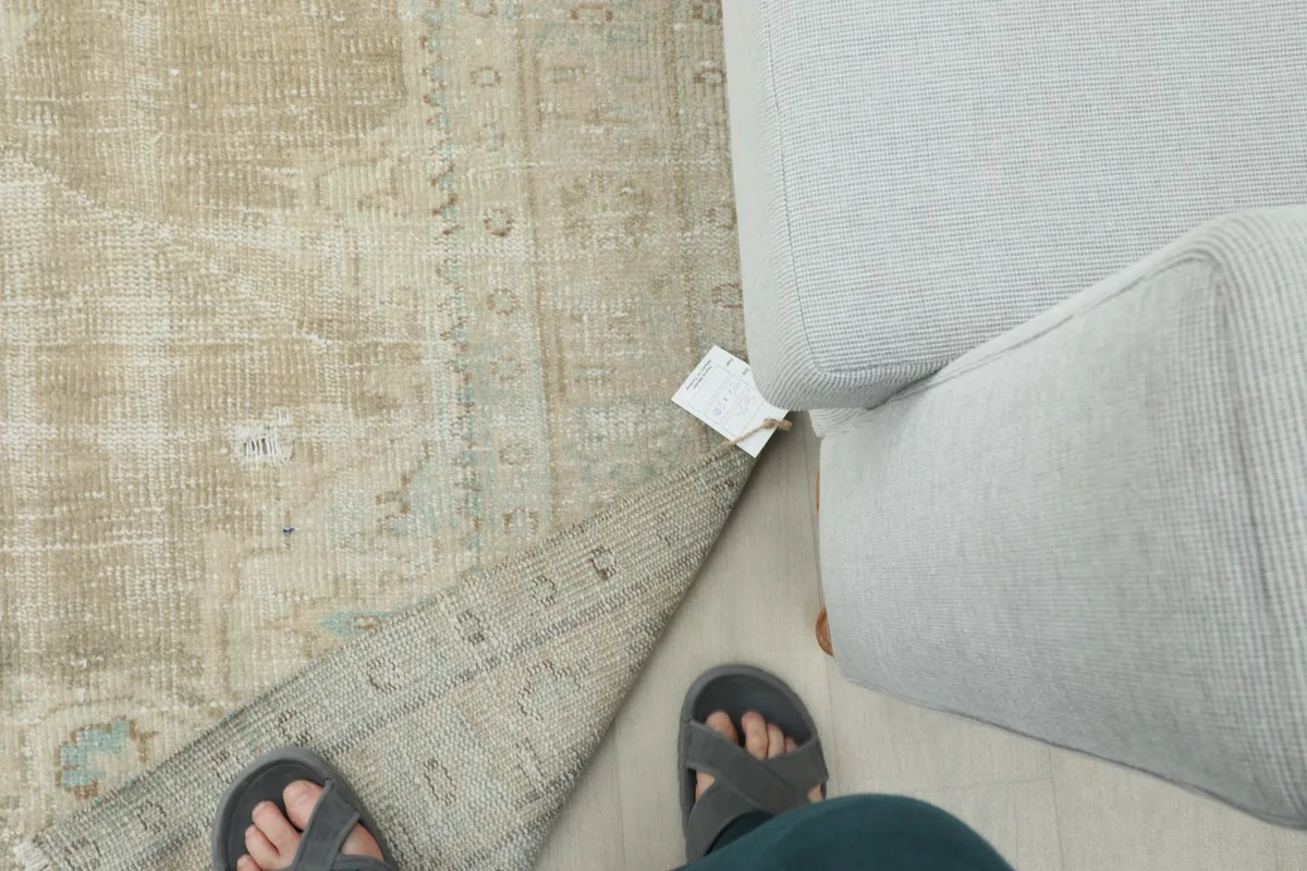 Top-down view of the rug with a person's feet and a tag, showing scale and the rug's texture