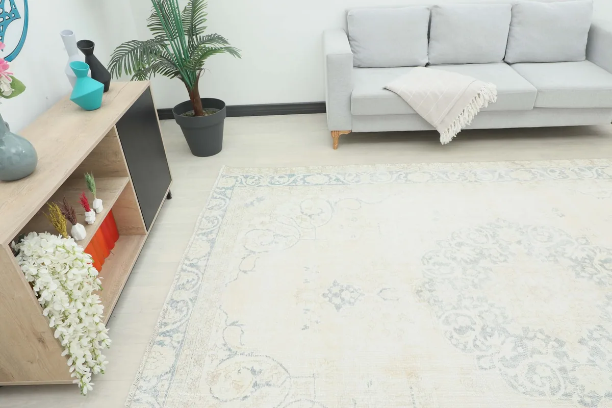 Angle view of the large ivory and blue rug in a living space with furniture.