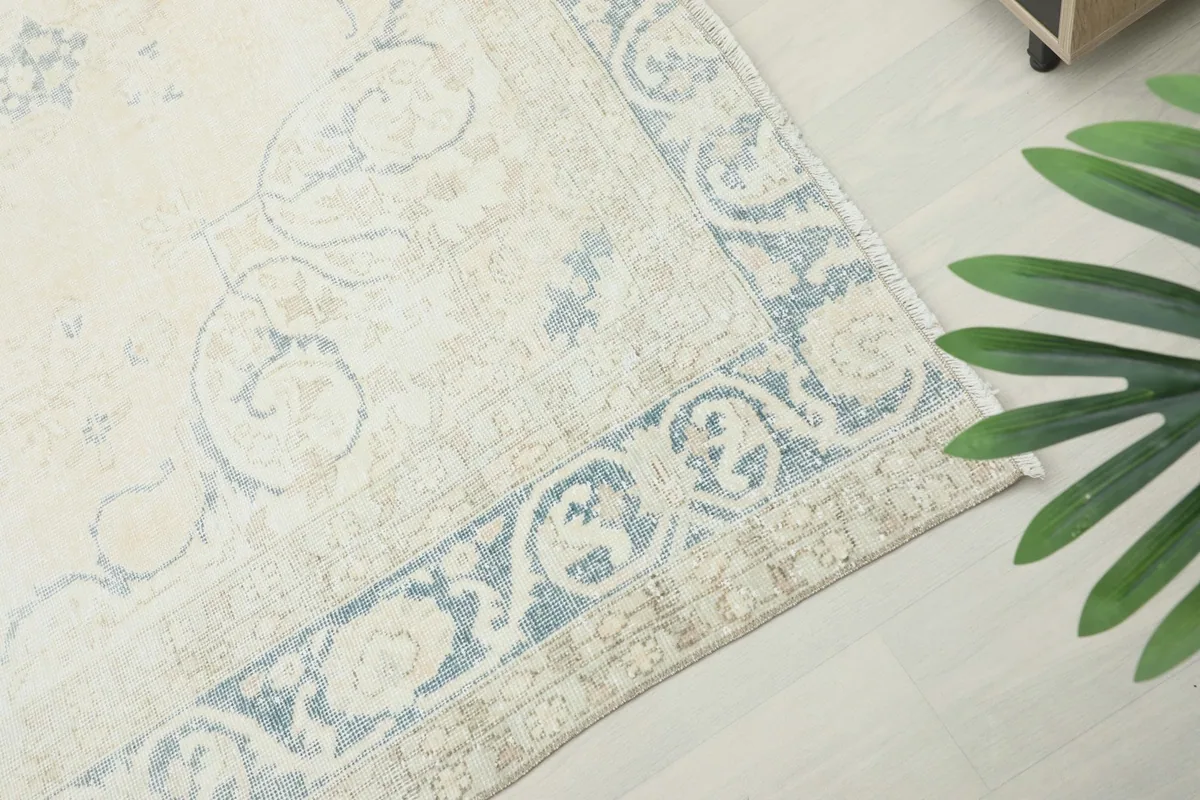 Corner detail of the rug's border, highlighting the faded blue and ivory floral motifs.