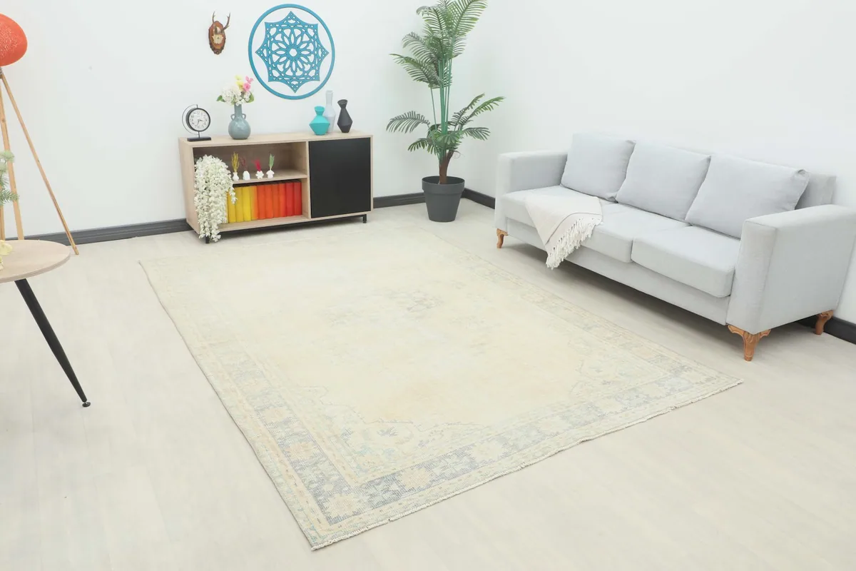 Vintage ivory rug displayed in a living room setting with a gray sofa and light wood furniture