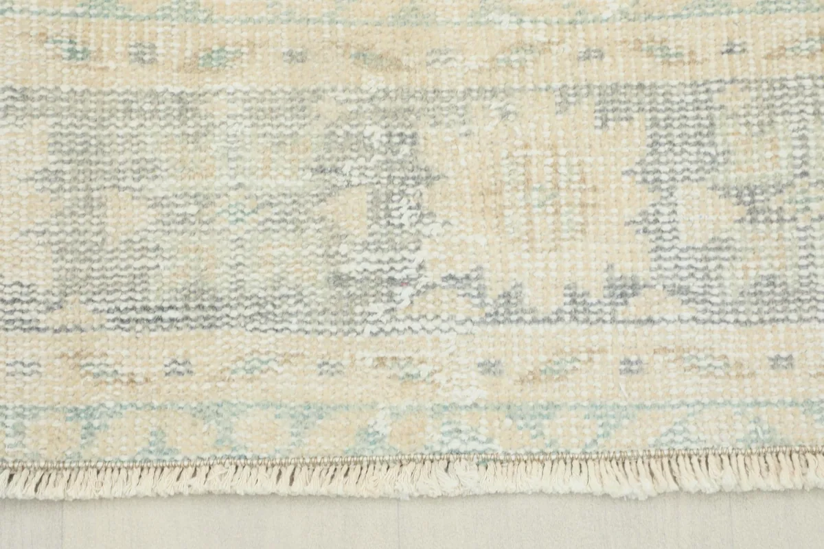 Close-up view showing the faded gray and blue geometric border patterns and the low pile texture