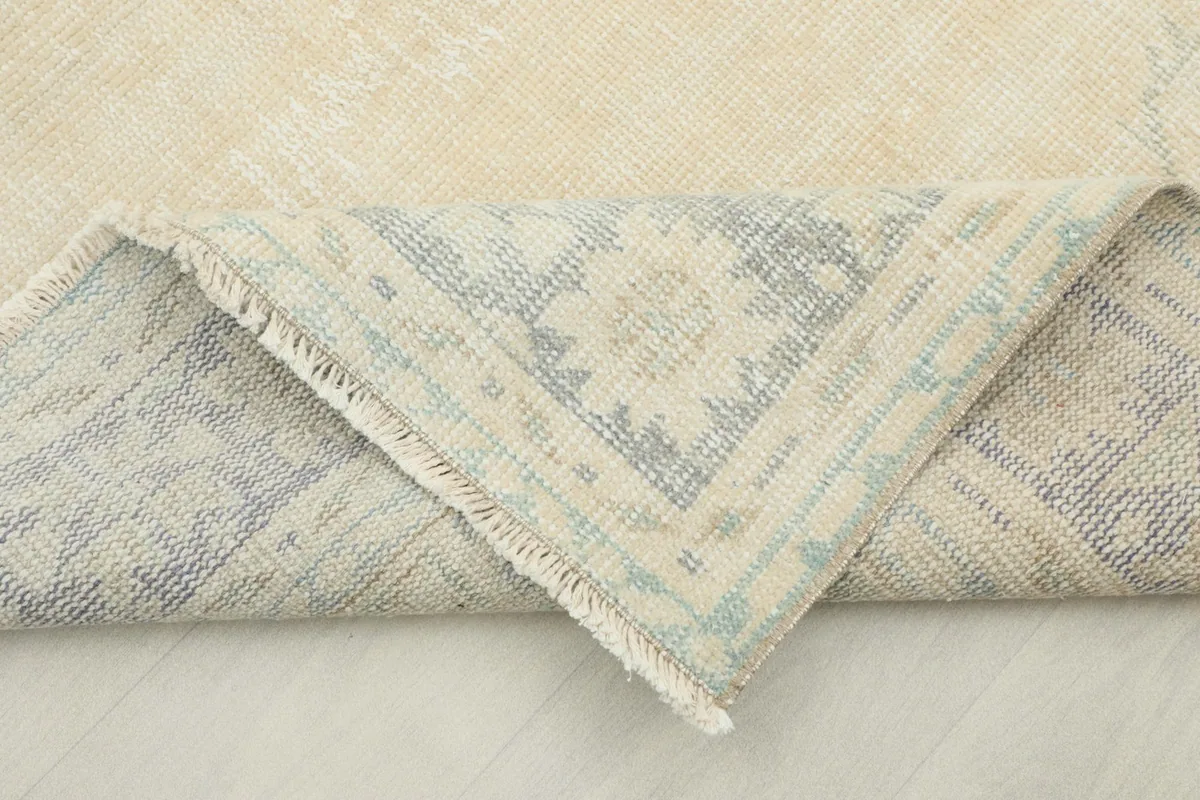 Corner of the rug folded back to reveal the back of the hand-knotted cotton foundation