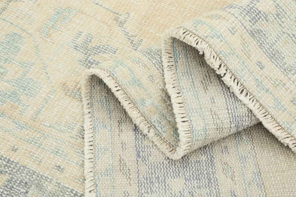 Close-up of the folded rug, showing the fringe and the construction of the wool pile and foundation