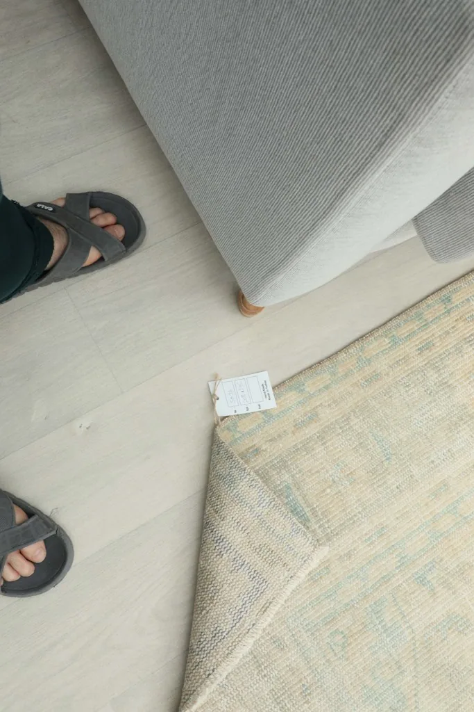 Overhead view showing the rug's label and the person's feet for scale and perspective
