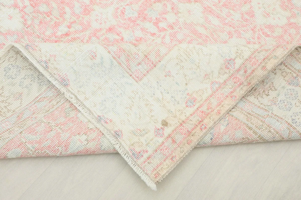 Corner of the rug folded to reveal the backside, showing the hand-knotted cotton foundation.