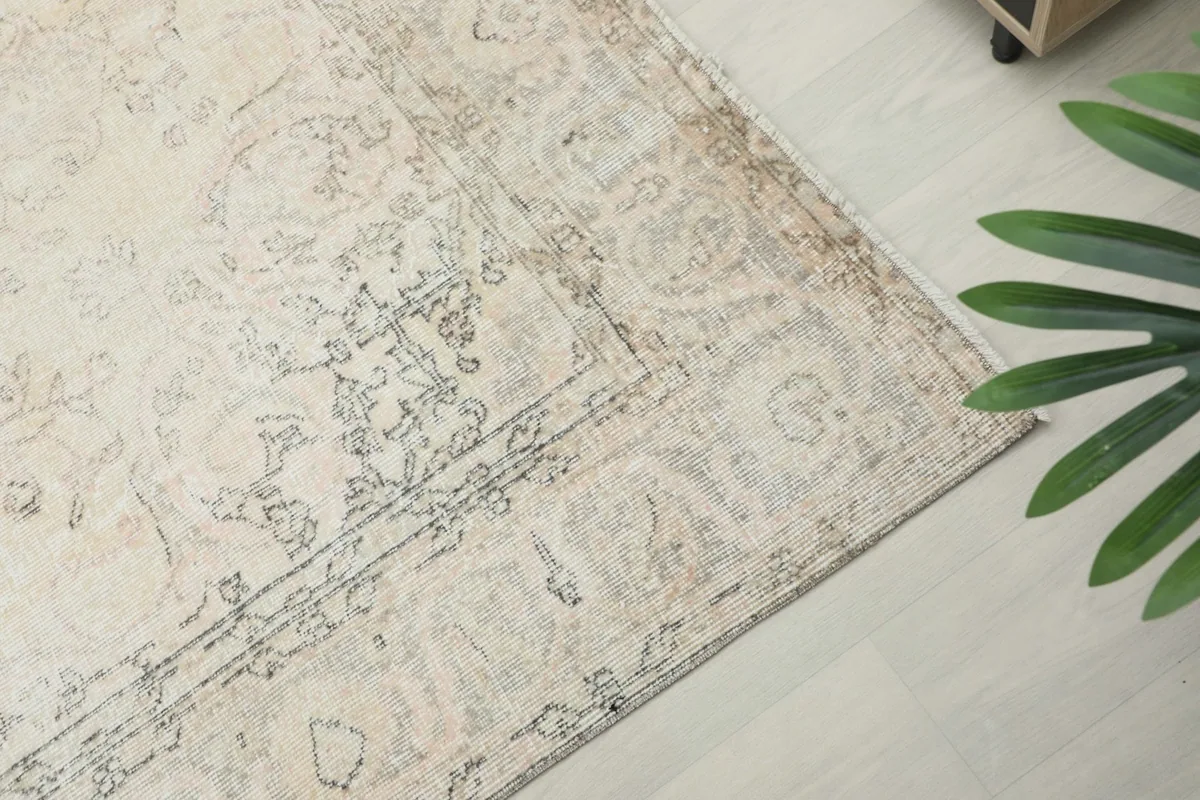Angled view of the rug's corner, highlighting the low pile and the delicate tan and gray border.
