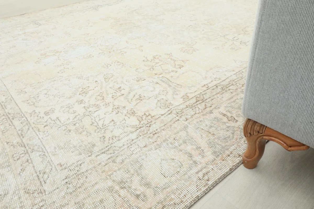 Corner of the rug next to a sofa leg, illustrating the rug's placement and scale in a room.