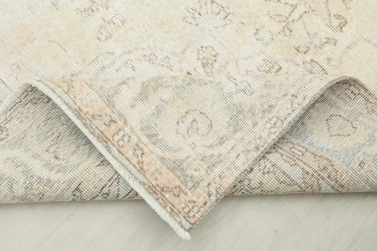 Corner of the rug folded back to reveal the hand-knotted cotton foundation and wool pile.