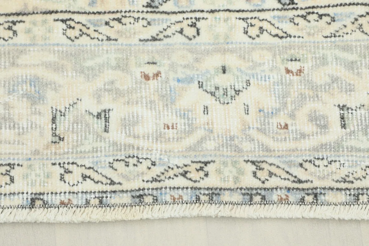Close-up detail of the border showing intricate blue, gray, and tan patterns and fringe.