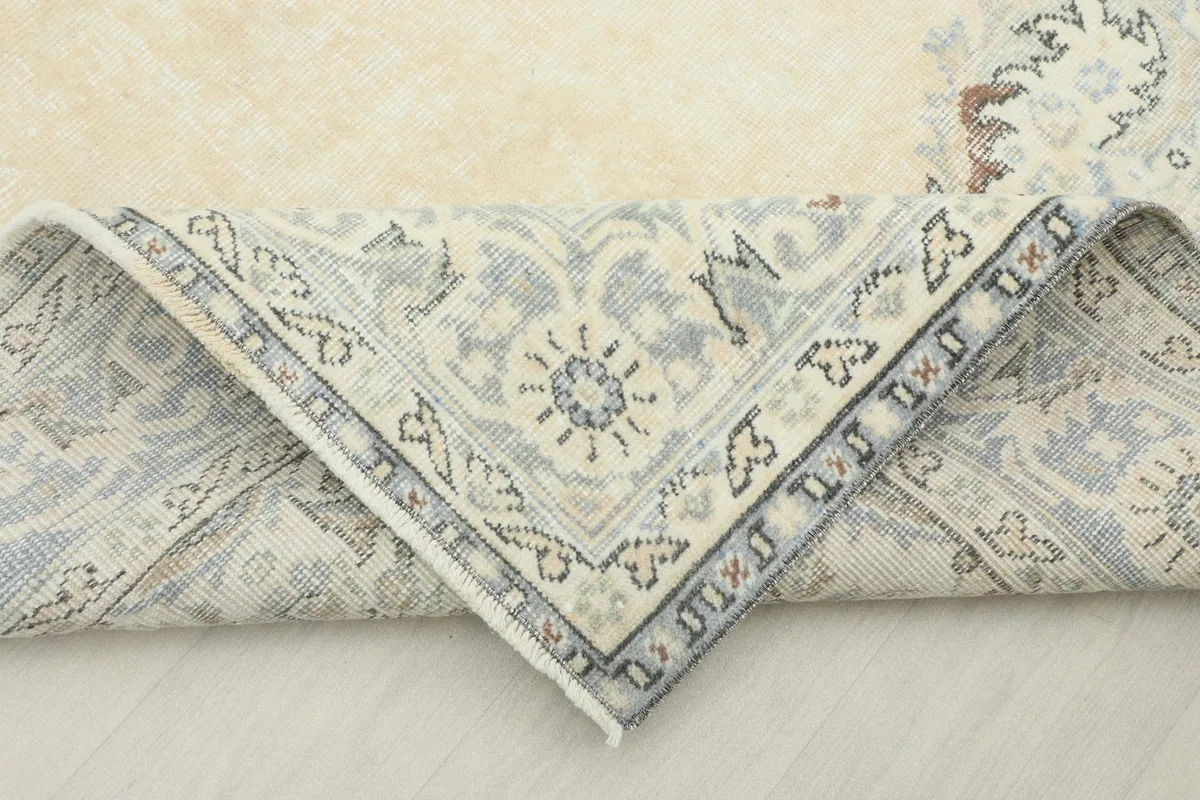 Corner of the rug folded back to reveal the cotton foundation and reverse side of the hand-knotting.
