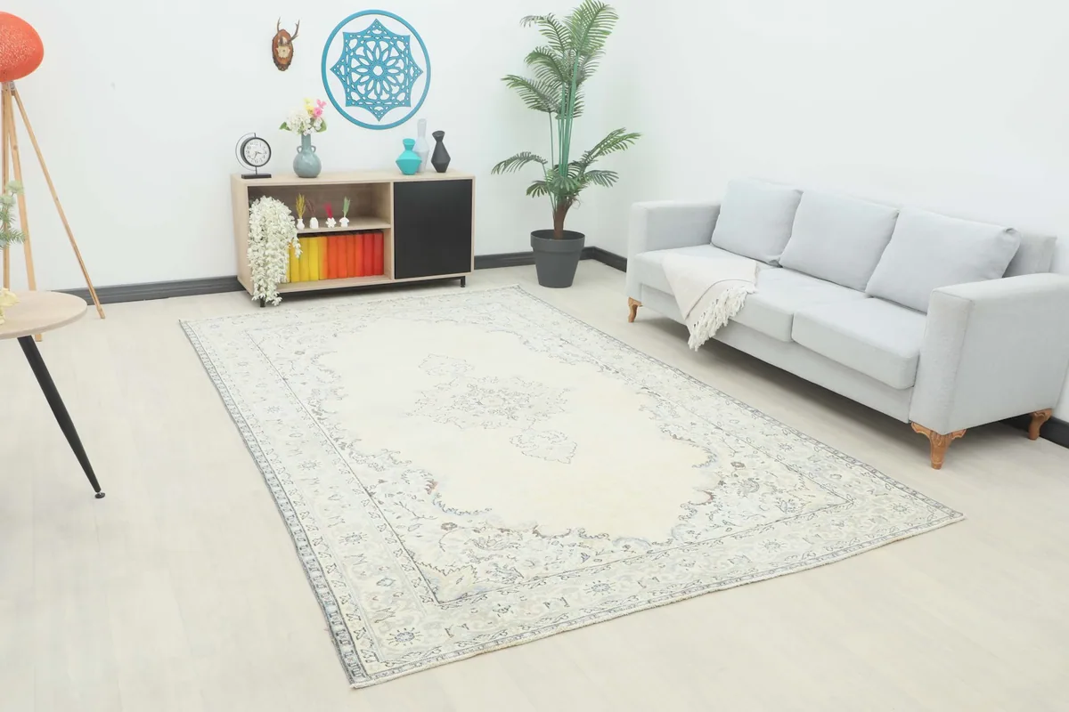 Overhead view showing the full ivory rug in a styled room setting with a light gray sofa.