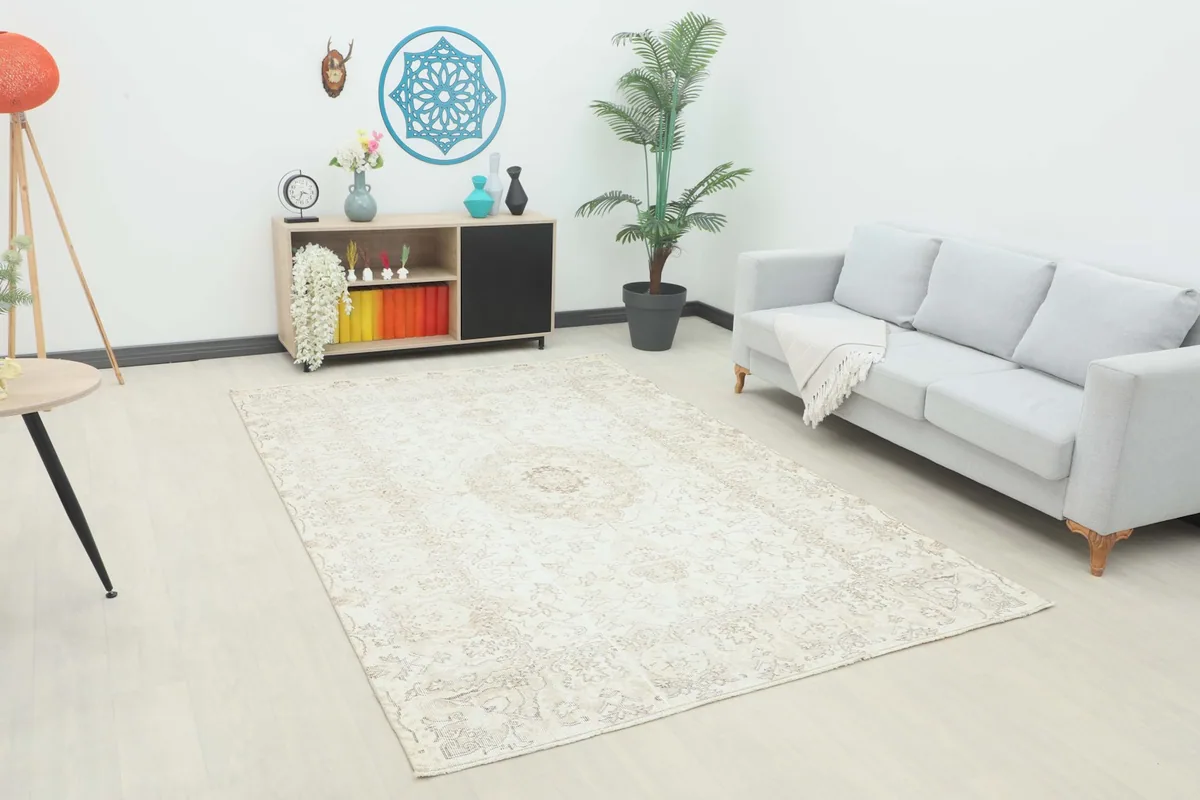 Vintage Anatolian area rug in an ivory and beige color scheme placed in a bright living room setting.