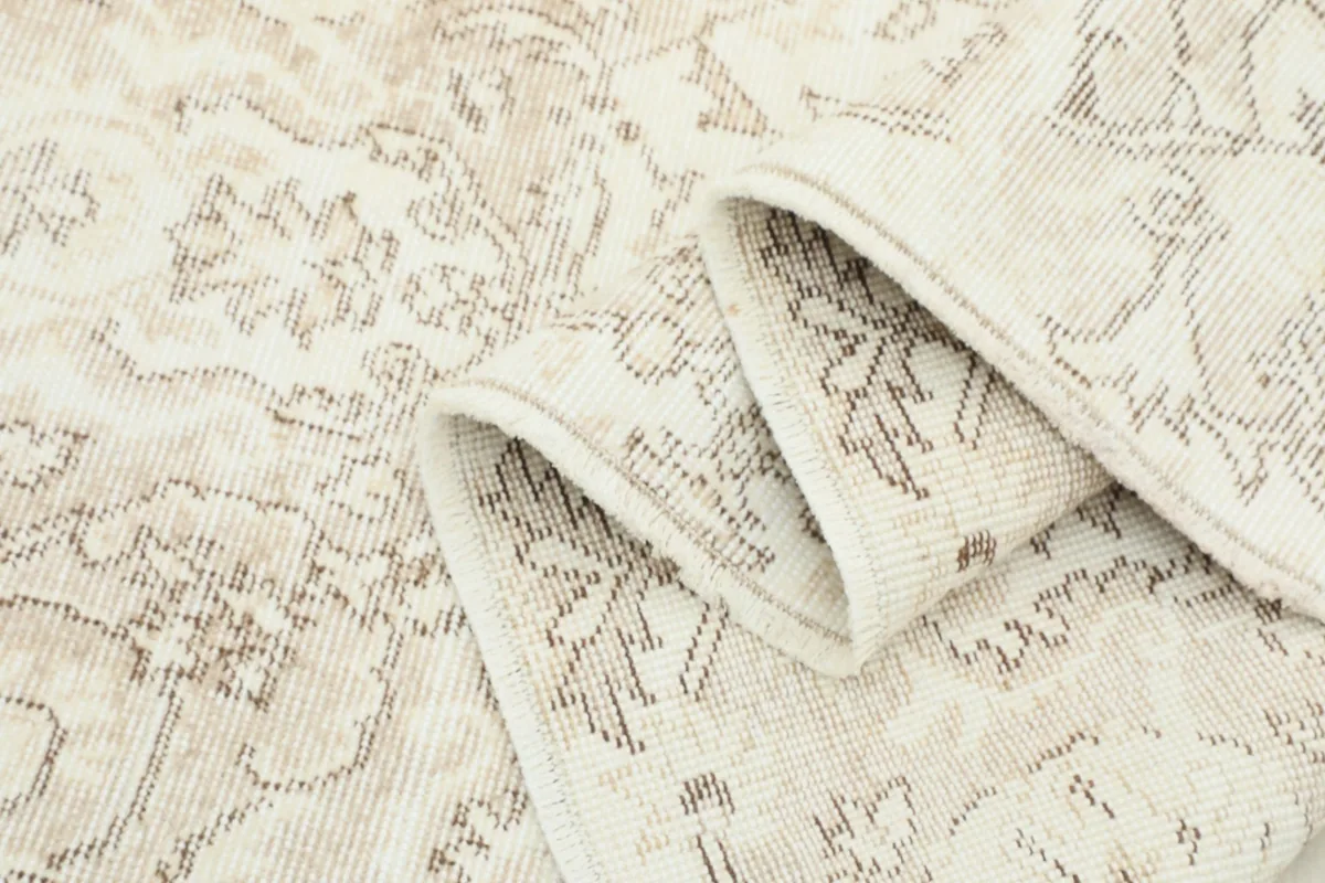 Folded section of the rug, showcasing the low wool pile and the vintage wear.