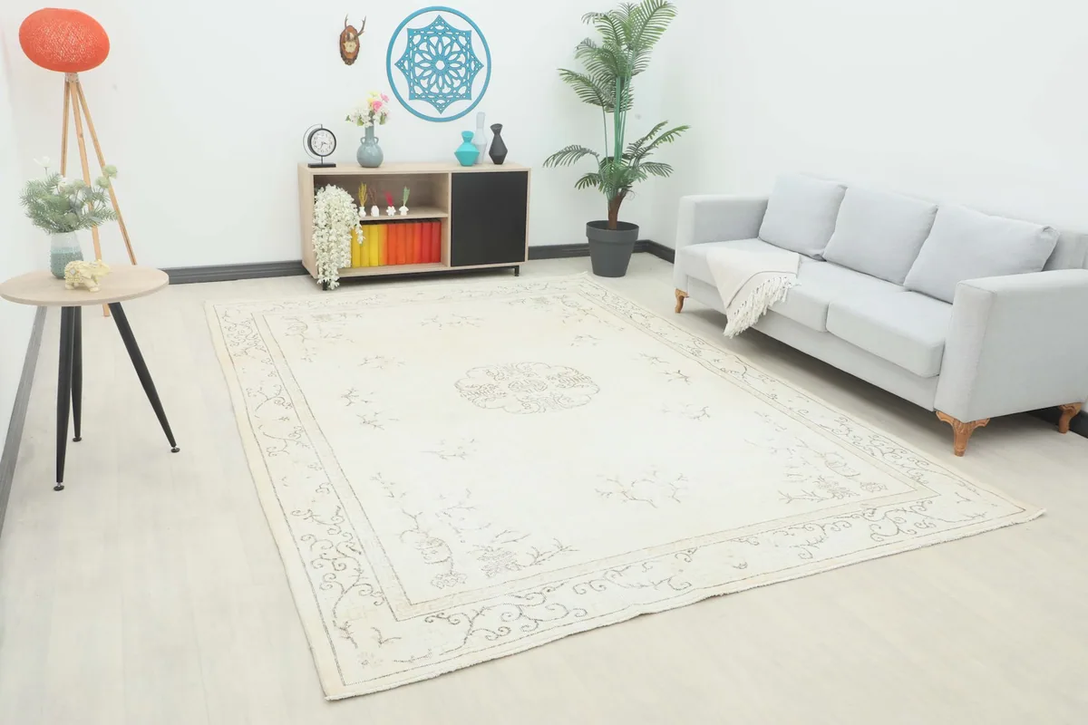 Angle view of the cream vintage rug in a room setting with a sofa and side table
