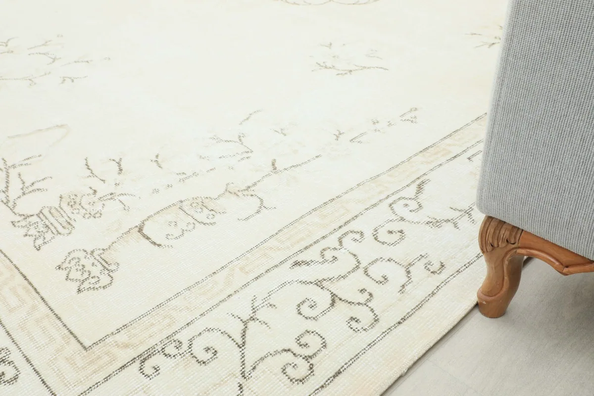 Partial view of the rug's border and field, with the leg of a piece of furniture in the foreground