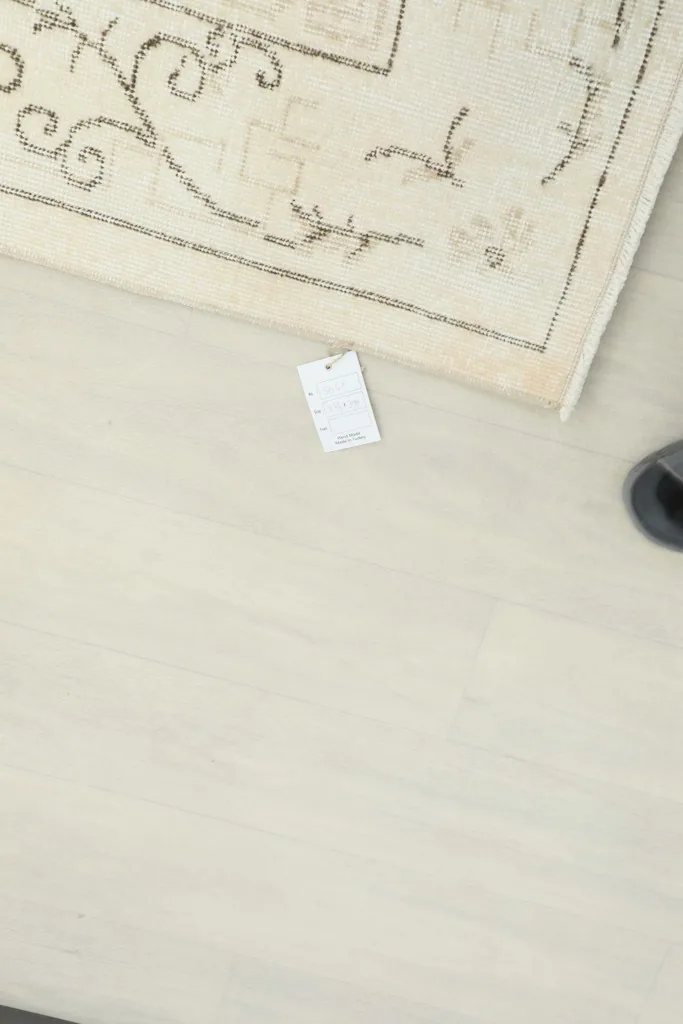 Overhead view of a corner of the rug with a label, showing the light floor beneath