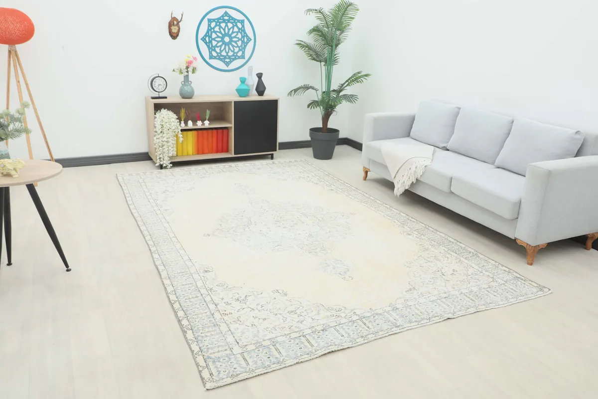 Angle view of the ivory area rug in a room setting with a sofa and plant