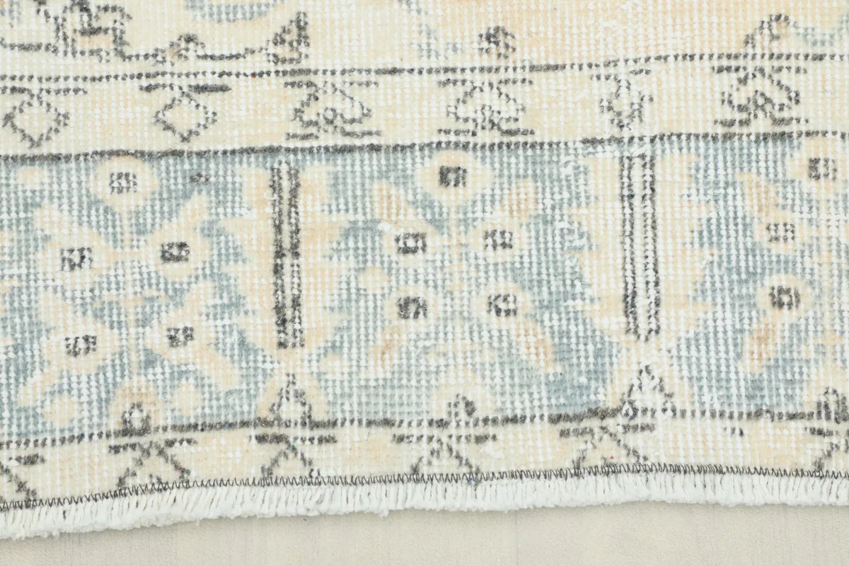 Close-up detail of the blue and gray geometric border pattern on the vintage rug