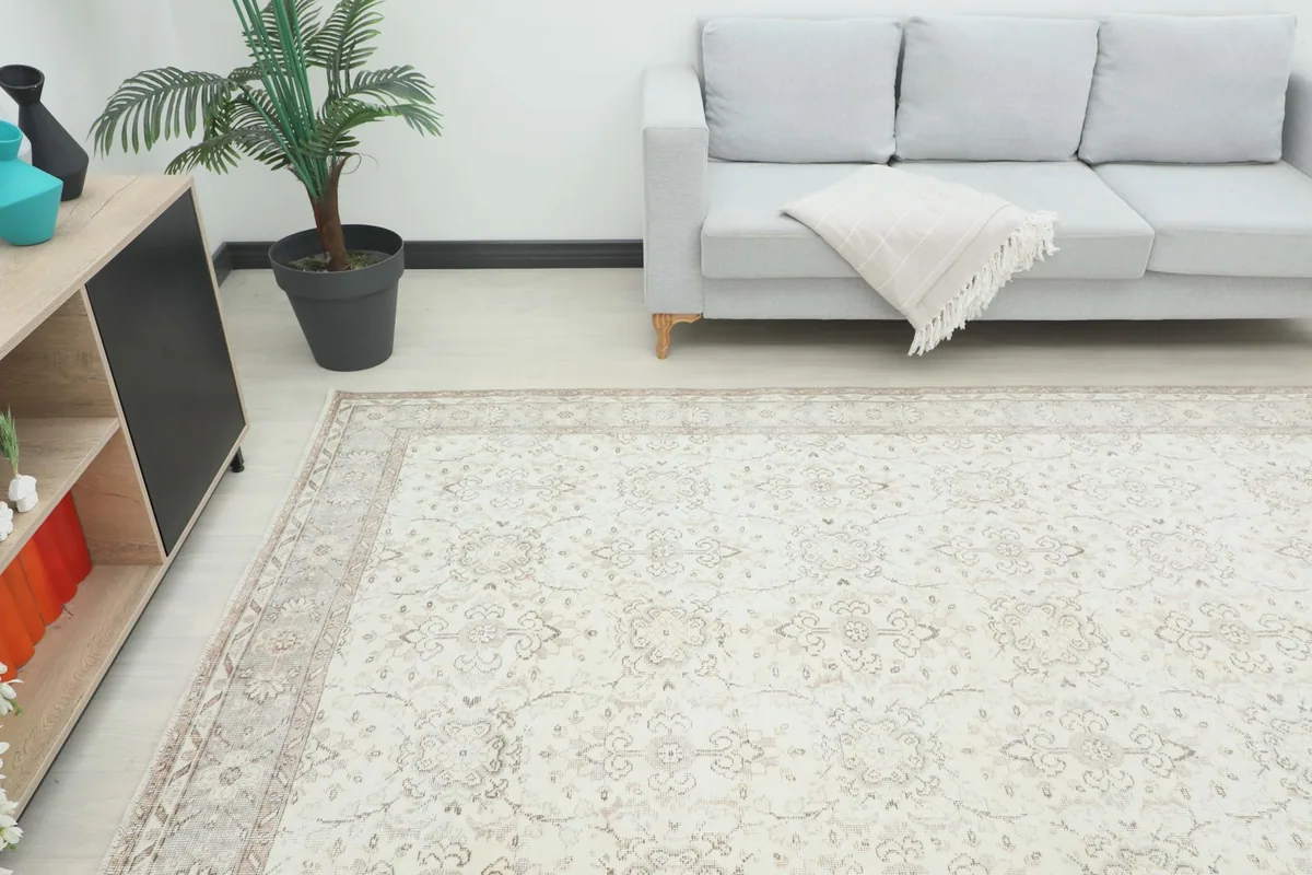 Angle view of the ivory beige rug in a living room setup, showing its scale next to furniture.
