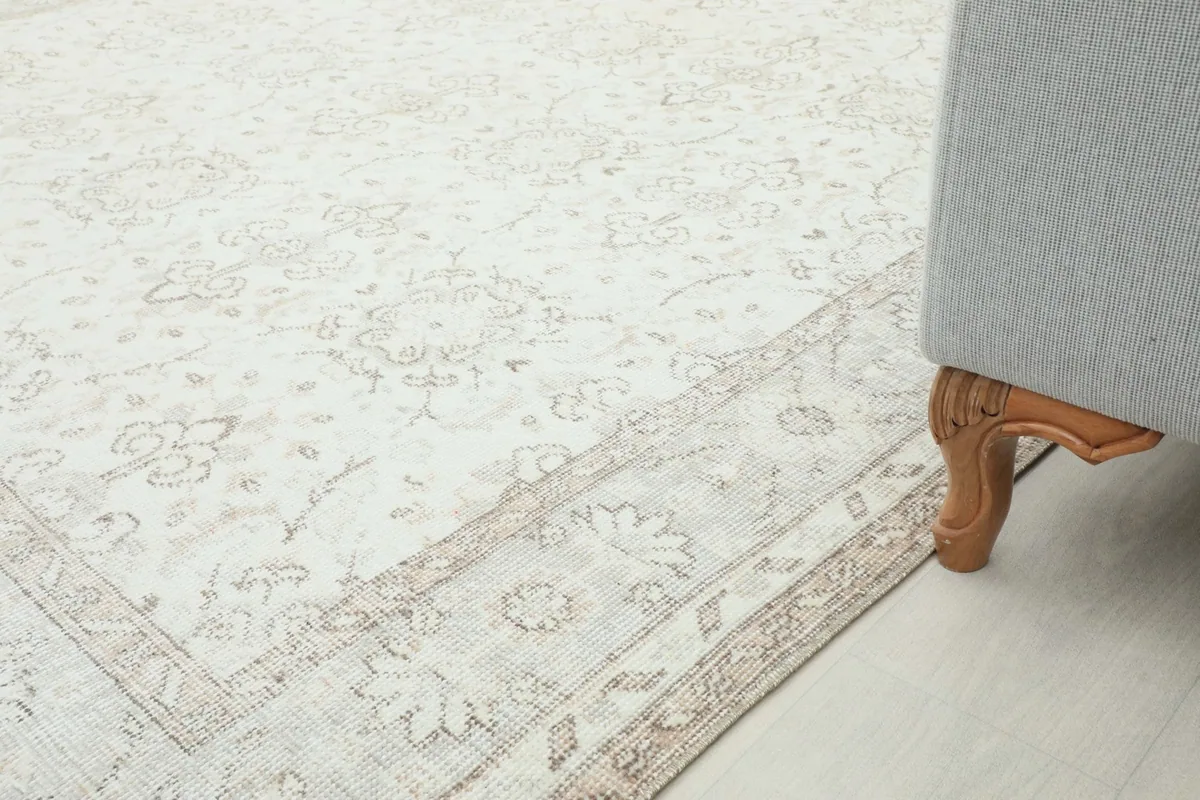 Close-up of the rug's edge next to a sofa leg, illustrating its placement in a home setting.