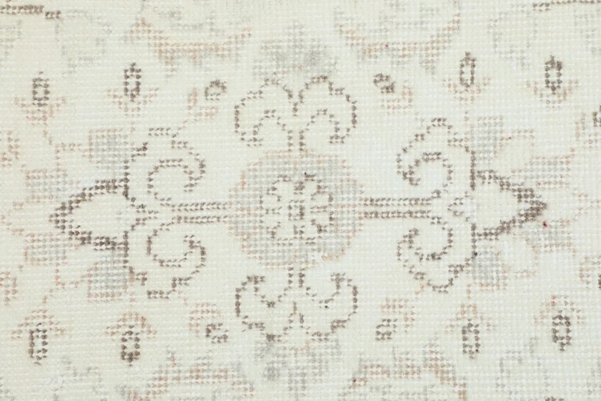 Macro shot highlighting the specific floral-like motif in muted beige and tan threads.