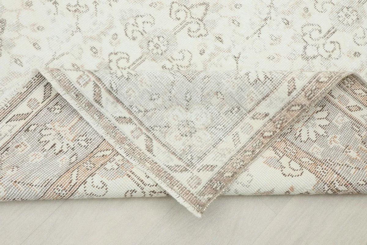 View of the rug's reverse side and a folded corner, revealing the cotton foundation and knotting.