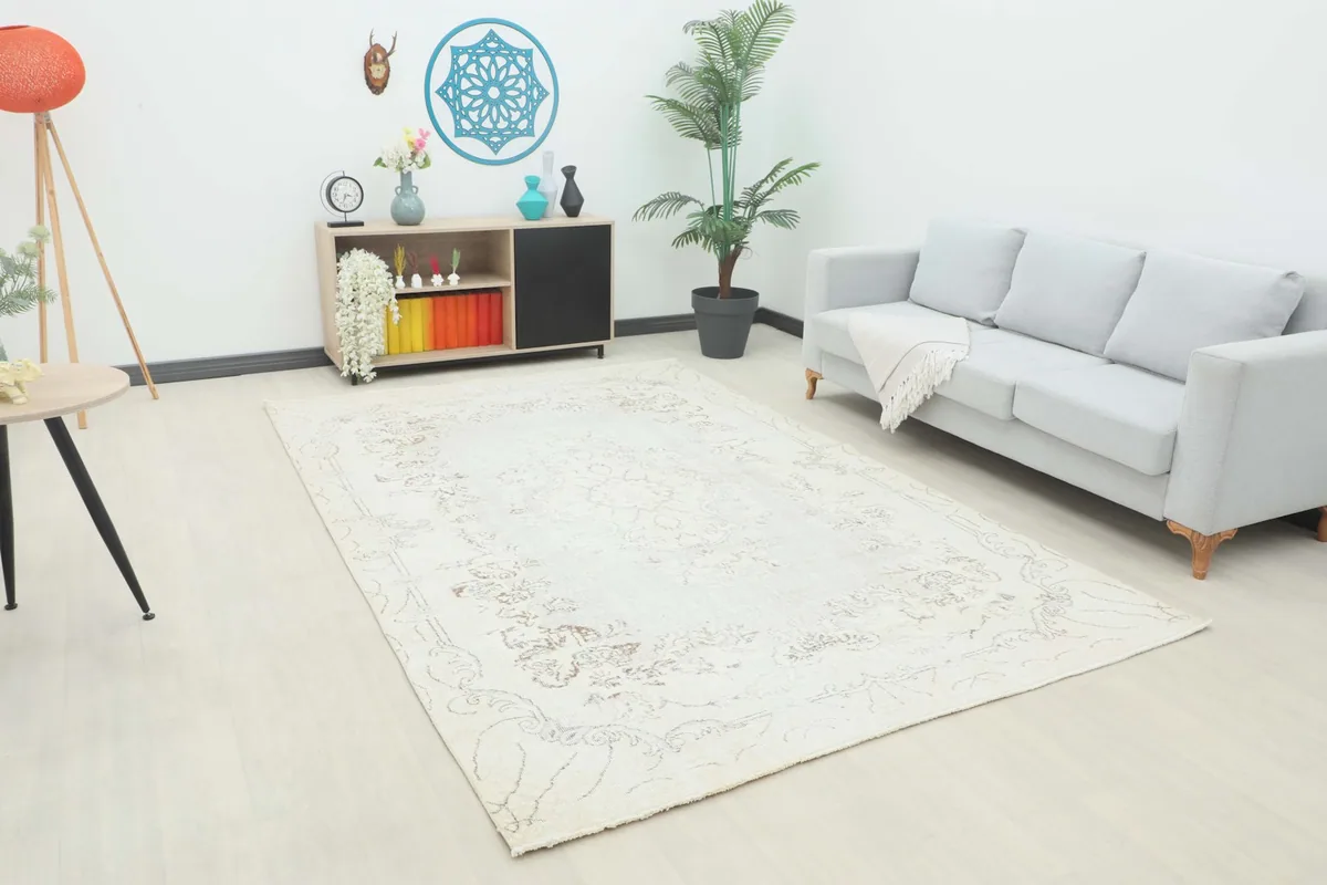 Cream vintage Anatolian rug laid out in a modern living space with a gray sofa.