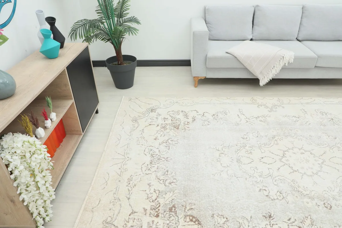 Angle view of the cream vintage rug in a living room setting, showing its scale.