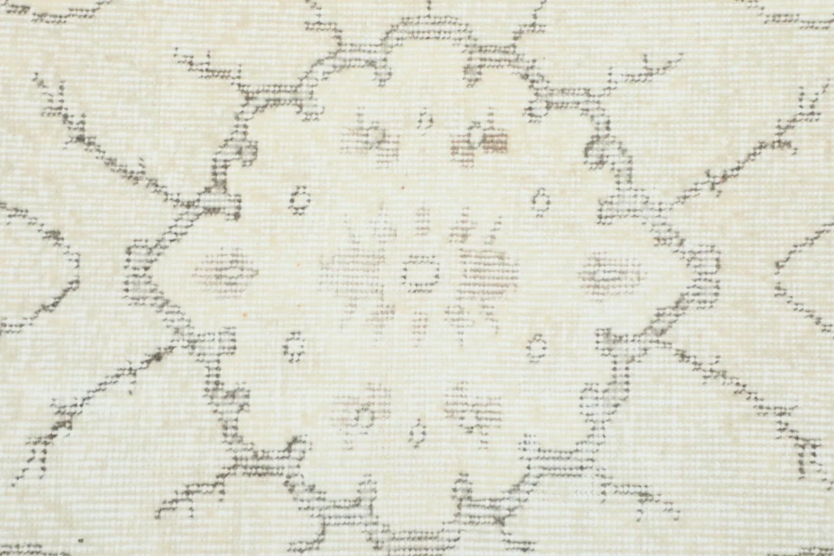 Close-up of a faded floral motif within the rug's pattern, showing texture.