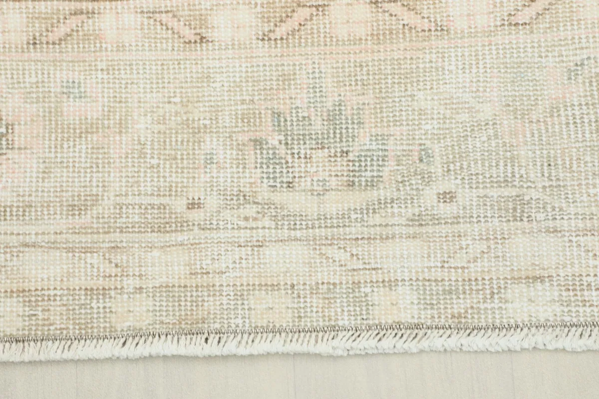 Close-up of the rug's border pattern showing subtle beige, tan, and gray tones