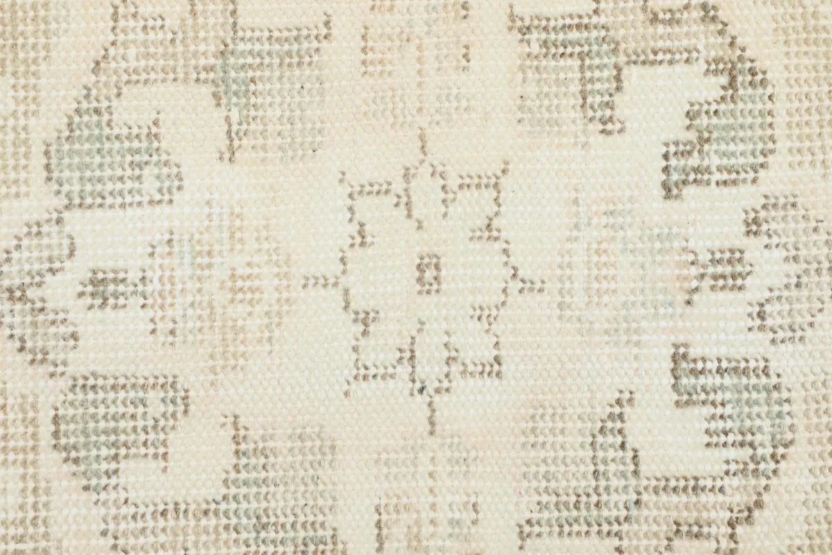 Close-up of the low pile texture and faded geometric patterns in the rug's field